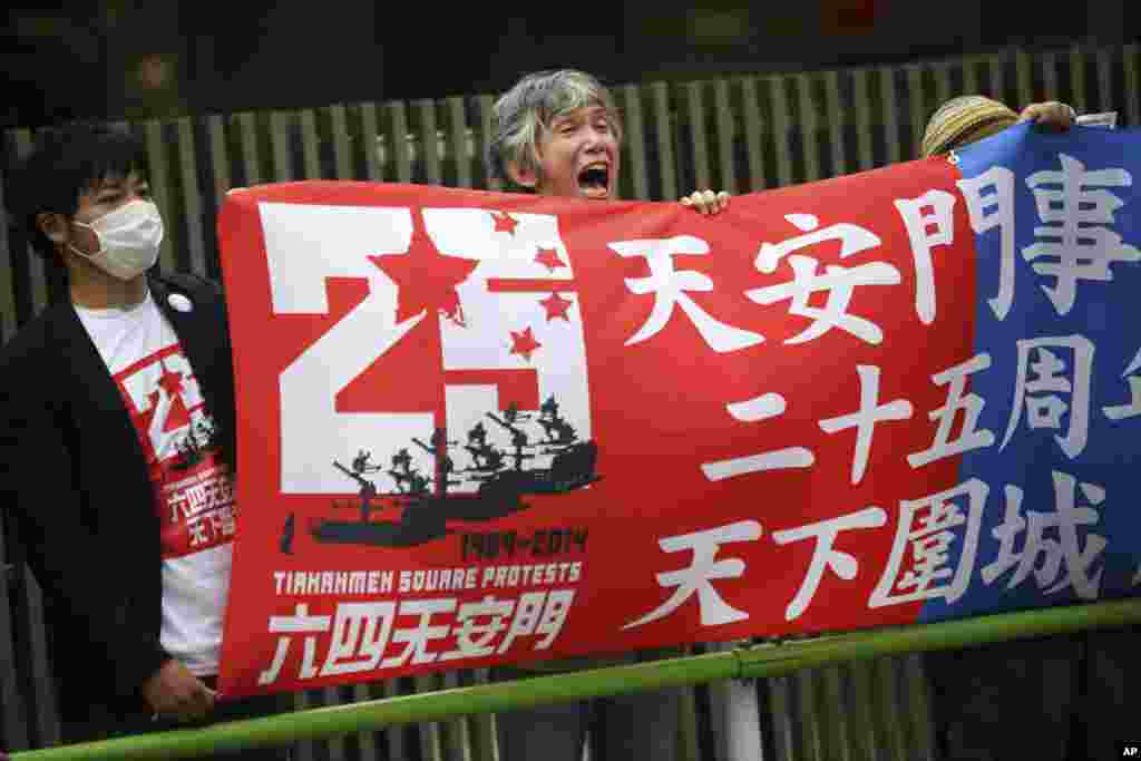 A protester holds a banner with others and shouts slogans in front of the Chinese Embassy in Tokyo, June 4, 2014.