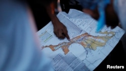 FILE - A migrant, part of a caravan of thousands traveling from Central America to the United States, points at a map while resting in Santiago Niltepec, Mexico, Oct. 29, 2018.