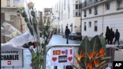 FILE - Flowers are attached to security fences outside Charlie Hebdo headquarters in Paris, one week after the attack on the magazine, Jan. 14, 2015.