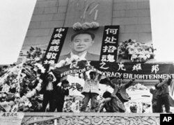 中国学生在北京天安门广场上的人民英雄纪念碑前展示胡耀邦像和“民主之光耀邦”等标语（1989年4月19日）