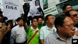 Protesters raise a mock "white paper", left, released by Beijing State Council on Tuesday saying it holds ultimate control over the former British colony, outside the Chinese liaison office in Hong Kong, June 11, 2014. 