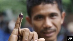 Seorang pria menunjukkan jarinya usai memberikan suara di salah satu TPS di Jakarta, Rabu (15/2).