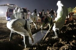 Penggali kubur mengenakan alat pelindung diri (APD) mengubur peti mati saat kerabat berdiri di belakang pemakaman Muslim yang disediakan pemerintah untuk korban COVID-19, di Jakarta, 7 Juli 2021. (Foto: REUTERS/Willy Kurniawan)