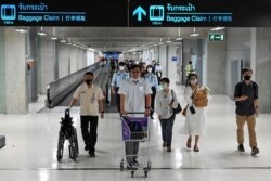 Para calon penumpang menggunakan alat pelindung diri berjalan di koridor menuju pemberangkatan di Bandara Internasional Suvarnabhumi, Thailand, Agustus 2020. (Foto: AFP)