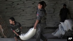 FILE - Palestinians receive UNRWA food aid at a U.N. warehouse at Shati refugee camp, in Gaza City, Jan. 14, 2018.