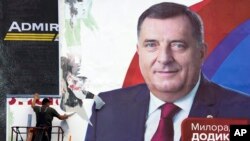 ARHIVA - Radnik uklanja plakat sa likom Milorada Dodika po završetku izbora u Banja Luci, 3. oktobra 2022. (Foto: AP/Darko Vojinović)