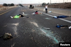 A man takes a photo of dead people strewn across a road n the Sderot area, southern Israel, following a mass-infiltration by Hamas gunmen from the Gaza Strip, Oct. 7, 2023.