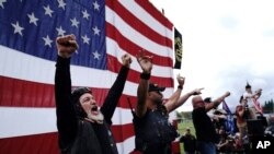 Anggota Proud Boys bersorak di atas panggung saat mereka dan demonstran sayap kanan lainnya berunjuk rasa, Sabtu, 26 September 2020, di Portland, Ore. (Foto: AP/John Locher)