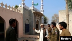 Seorang warga desa berbicara dengan polisi di sebuah masjid di desa Tulamba, Mian Channu, Pakistan, setelah seorang pria dibunuh oleh sekelompok massa karena pria tersebut diduga membakar Al-Qur'an, pada 13 Februari 2022. (Foto: Reuters/Arshad Raza)