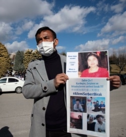 Uighur protester Mirza Ahmet Ilyasoglu holds photographs of relatives he says they have not heard from in years, speaks near the Chinese Embassy in Ankara, Turkey, Feb. 9, 2021.