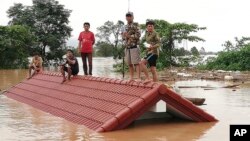 Villagers take refuge on a rooftop above floodwaters from a collapsed dam in the Attapeu district of southeastern Laos, July 24, 2018. 