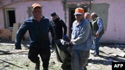 Чоловіки виносять тіло загиблого внаслідок російської атаки, Харків, 30 квітня 2024. SERGEY BOBOK / AFP