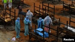 Relawan dan kerabat bersiap melakukan kremasi jenazah korban COVID-19 di desa Giddenahalli, pinggiran Bengaluru, India, 2 Mei 2021. (REUTERS/Samuel Rajkumar)