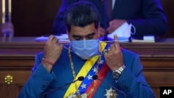 Presiden Venezuela Nicolás Maduro melepaskan maskernya sebelum
berpidato di hadapan anggota parlemen di Majelis Nasional, di Caracas, Venezuela, 12 Januari 2021.