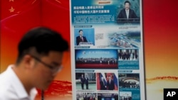 FILE - A man walks by a government billboard promoting Chinese President Xi Jinping's signature Belt and Road Initiative, outside a subway station in Beijing, China, Aug. 28, 2018. A new report shows China's overseas investments in the COVID-19 era are at a 13-year low.