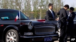 在北京首都机场，警卫人员守卫在一辆准备迎接法国总统奥朗德的红旗牌轿车旁。（2013年4月25日资料照）
