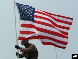 Seorang Marinir AS mengibarkan bendera Amerika di atas kendaraan serbu amfibi selama latihan militer bersama AS-Thailand di Pantai Hat Yao di Provinsi Chonburi, Thailand timur, Sabtu, 17 Februari 2018. (Foto: AP)