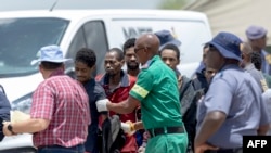 Illegal miners rescued from an abandoned gold mine line up as rescuers and South African Police Service officers record their details and provide assistance in Stilfontein on Jan. 14, 2025.