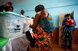 Perempuan sedang menggendong bayi di daerah Kiambu, Kenya, 8 Agustus 2017. (Foto: Reuters)