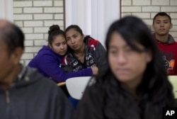 FILE - Central American migrants embrace as they wait for assistance at a center for newly arrived migrant families with children, at Sacred Heart Catholic Church in McAllen, Texas.