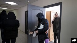 FILE - Police carry documents and computers out of the office of the Belarusian Association of Journalists as Andrei Bastunets, the head the Association, right, stands inside the office in Minsk, Feb. 16, 2021.