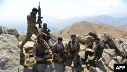 Members of anti-Taliban Afghan resistance forces rest as they patrol on a hilltop in the Darband area of Anaba district, Panjshir province, Afghanistan, Sept. 1, 2021.