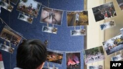FILE - This photograph taken on Nov. 14, 2020 shows a photographer in front of pictures depicting the 2019 campus siege at the height of the city's pro-democracy protests at an exhibition in the Chinese University of Hong Kong.