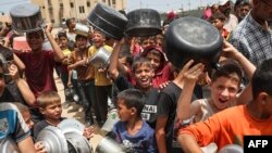 Anak-anak Palestina yang terlantar mengantre makanan di Rafah, di Jalur Gaza selatan, pada 19 Mei 2024, di tengah konflik yang sedang berlangsung antara Israel dan kelompok militan Hamas. (Foto: AFP)