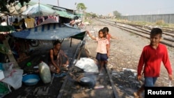 A woman cooks rice by a railway track in Phnom Penh, March 19, 2013. 