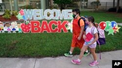Siswa mengenakan masker, berjalan melewati tanda "Selamat Kembali Bersekolah" pada hari pertama sekolah di SD Sessums, Riverview, Florida, 10 Agustus 2021. (AP Photo/Chris O'Meara, File)