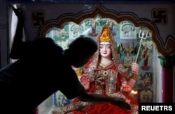 Seorang pemuja Hindu memegang dupa saat melakukan ritual di depan patung dewa. (Foto: Reuters)