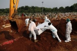 Pekerja mengenakan Alat Pelindung Diri (APD) mengubur peti mati pria berusia 72 tahun yang meninggal karena COVID-19 di area pemakaman di Bekasi, 15 Juli, 2021. (Foto: REUTERS/Willy Kurniawan)