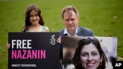 Richard Ratcliffe, suami dari Nazanin Zaghari-Ratcliffe, warga Inggris keturunan Iran yang ditahan di Iran, bersama anaknya Gabriella berpose untuk media dengan membawa foto sang istri, di London, Inggris, pada 23 September 2021. (Foto: AP/Matt Dunham)