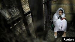 FILE - Aya Hijazi, founder of Belady, an NGO that promotes a better life for street children, reads in a holding cell while awaiting trial on charges of human trafficking at a courthouse in Cairo, Egypt, March 23, 2017.