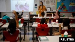 Seorang guru memberikan pelajaran di sebuah sekolah dasar yang dibuka kembali di Chelsea, Massachusetts, AS 15 September 2021.