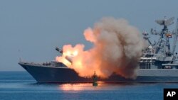Missiles are fired by a Russian navy battleship during a rehearsal of the Russian Navy Day parade in Sevastopol, Crimea, Ukraine. Friday, July 24, 2015. (AP Photo/Alexander Polegenko)