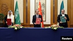 Diplomat senior China Wang Yi (tengah) memediasi normalisasi hubungan diplomatik Arab Saudi dan Iran, dengan penandatanganan kesepakatan oleh pejabat Saudi Musaad bin Mohammed Al Aiban (kiri) dan pejabat Iran, Ali Shamkhani, di Beijing 10 Maret 2023. 