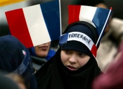 Seorang gadis Muslim muda dengan dua bendera Prancis dan ikat kepala bertuliskan "Persaudaraan" menarik jilbabnya berbaris di antara sekitar 3.000 Sikh dari seluruh Eropa 31 Januari 2003. (Foto: Reuters)