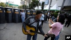 Seorang perempuan berfoto dekat peralatan anti huru-hara sehari setelah bentrokan antara pendukung capres Prabowo Subianto dan aparat keamanan, di Jakarta, 23 Mei 2019. (Foto: AP)