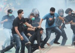 Polisi menahan para demonstran di tengah asap gas air mata dalam aksi yang berakhir rusuh di Jakarta, Kamis (8/10).