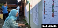 Seorang pemilih memeriksa daftar legislatif yang dipasang di sebuah TPS di Sleman, DIY dalam Pemilu 2019. (Foto: VOA/ Nurhadi)