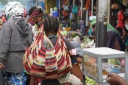 Seorang ibu membawa noken di sebuah pasar di Papua. (Foto: Alam Burhanan/VOA)