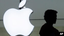 Seseorang berdiri di dekat logo 'Apple' di toko Apple di New York (foto: dok).