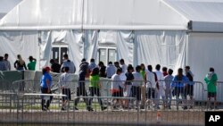 FILE - Detained migrant children from Central America line up to enter a tent at the Homestead Temporary Shelter for Unaccompanied Children in Homestead, Florida, Feb. 19, 2019. 