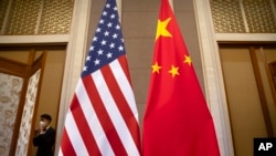 Seorang staf mengenakan masker saat berjalan melewati bendera Amerika Serikat dan China menjelang pertemuan Menteri Keuangan AS Janet Yellen dan Wakil Perdana Menteri China He Lifeng di Wisma Negara Diaoyutai, di Beijing, China, 8 Juli 2023. (Foto: Mark Schiefelbein/AP Photo)