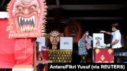 Seorang perempuan memakai masker saat memberikan suara Pilkada di Badung, Provinsi Bali. Pilkada serentak diselenggarakan di tengah pandemi Covid-19 (Foto ilustrasi: Antara/Fikri Yusuf via Reuters)