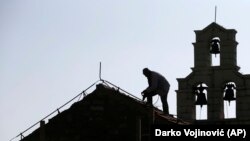 Radnik popravlja krov na crkvi Svete nedelje (Foto: AP/Darko Vojinović)