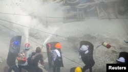 Tear gas and fire extinguisher gas float around protesters as they clash with riot police officers during a protest against the military coup in Yangon, Myanmar, March 1, 2021.