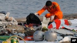 Član tima za spasavanje i potragu skuplja ostatke indonežanskog aviona
