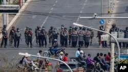 Police stand in formation blocking a main road in Mandalay, Myanmar, Feb. 27, 2021. 